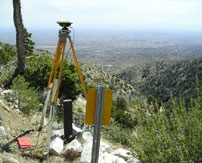 A tripod survey tool on a grassy hillside