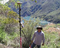 Tripod survey tool on a rough hillside and a Johnson-Frank surveyor standing beside it